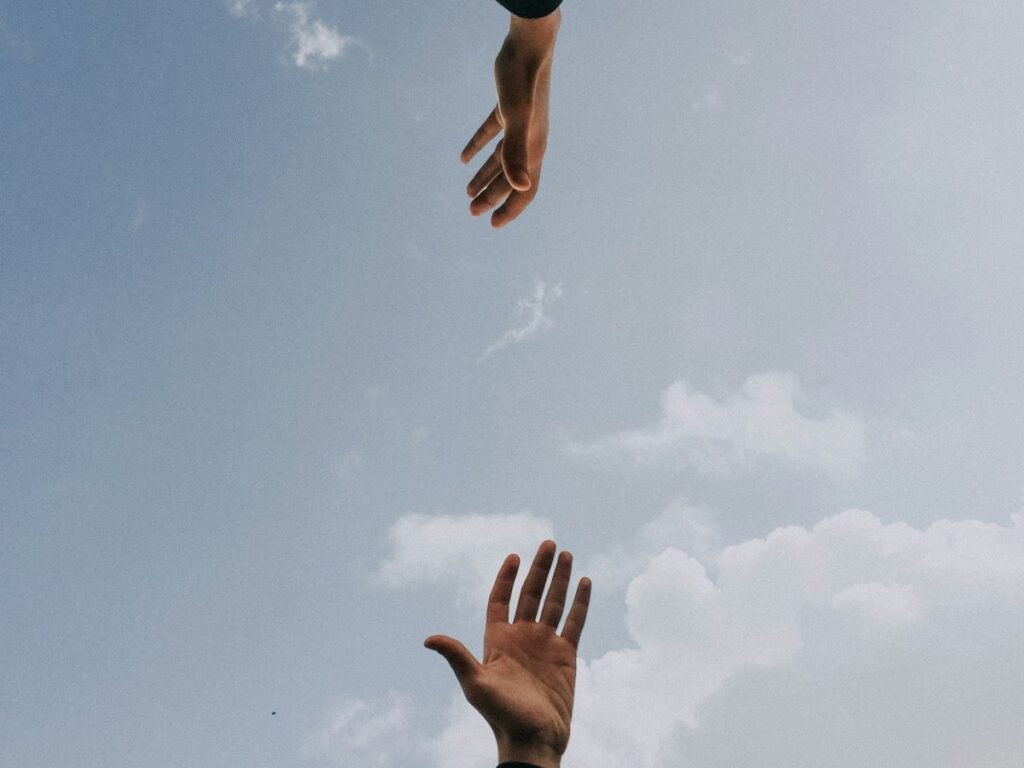 Duas mãos se aproximando contra o céu azul